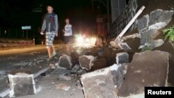 Local residents walk next to a collapsed wall after a powerful April 14 earthquake in the town of Mashiki in southern Japan. 