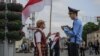 Ніна Багінская і міліцыянт падчас акцыі «Праспэкт нацыянальнага сьцяга», архіўнае фота