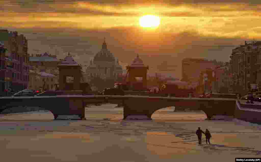 A couple in St. Petersburg walk on the ice of the frozen Fontanka River with Troitsky Cathedral in the background. (AP/Dmitry Lovetsky)