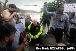 Polițiști și manifestanți îngenunchează împreună în semn de protest față de uciderea lui George Floyd, Sunrise, Florida, 2 iunie 2020.