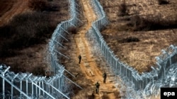 Soldiers patrol between a razor wire fence marking North Macedonia's border with EU member Greece. (file photo)