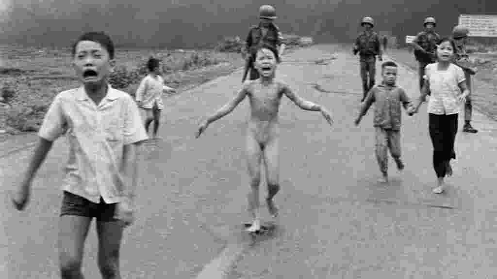 Девятилетняя Фан Тхи Ким Фук (в центре), сорвавшая с себя горящую одежду, с другими вьетнамскими детьми бежит после атаки напалмовыми бомбами 8 июня 1972 года. Южновьетнамский вертолет ошибочно сбросил бомбы на южновьетнамскую деревню. Ким Фук стала символом пострадавших мирных жителей во время Вьетнамской войны. 