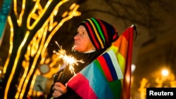 A demonstrator holds a rainbow flag and the Russian national flag during a protest outside the Russian Embassy in Berlin on December 12 calling on Russian authorities to lift antigay laws ahead of the Sochi 2014 Olympics.