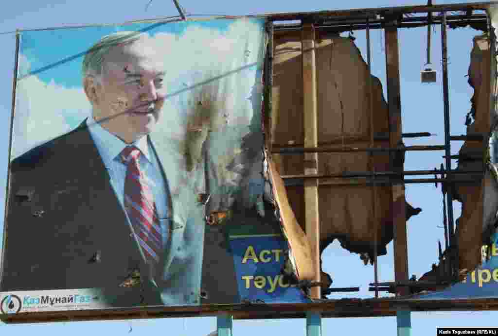 On the streets of Zhanaozen, a burnt-out banner featuring Kazakh President Nursultan Nazarbaev.