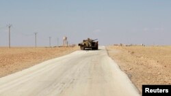 A damaged armored vehicle is pictured along a deserted road in the countryside near Kobani after Islamic State fighters took control of the area.