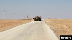 A damaged armored vehicle is pictured along a deserted road in the countryside near Kobani after Islamic State fighters took control of the area.