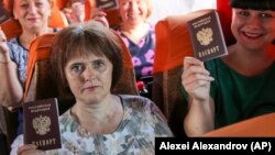 Люди демонструють свої російські паспорти, сидячи в автобусі до Росії на автобусній зупинці в Донецьку, 2020 рік.
