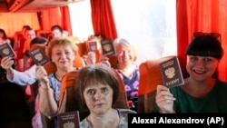 Люди показывают свои российские паспорта во время остановки автобуса в Донецке, 27 июня 2020 года
