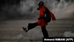 Një protestues largon një gaz lotsjellës të hedhur nga policia. Tiranë, 25 tetor 2026. 
