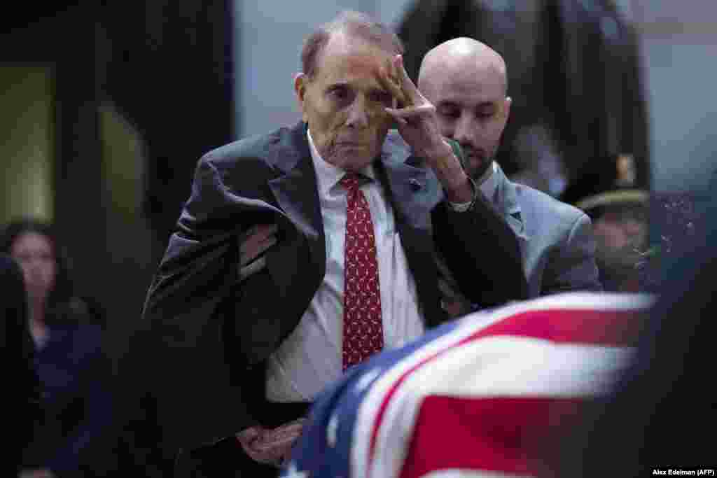 Former U.S. Senator Bob Dole, a World War II veteran who is 95, asked an aide to help him stand up from his wheelchair to salute the flag-draped coffin of former U.S. President George Bush at the U.S. Capitol rotunda on December 4 in Washington. Bush, the 41st U.S. president, died on November 30 at the age of 94. (AFP/Alex Edelman / AFP)