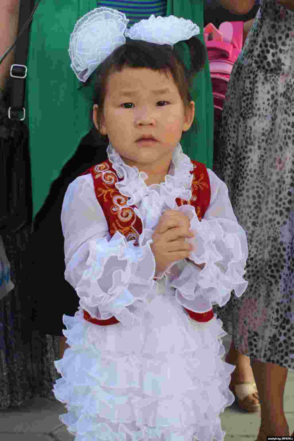 Маленькая девочка в национальном платье на школьной линейке в честь начала учебного года. Бишкек, 1 сентября 2012 года.