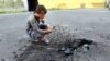 A young boy takes a picture of a crater left in the asphalt in the eastern city of Donetsk.