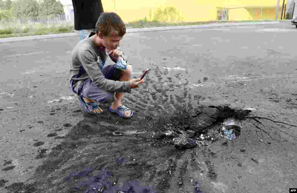 Хлопчик фотографує на телефон воронку від вибуху снаряда, Донецьк, 22 липня 2014 року