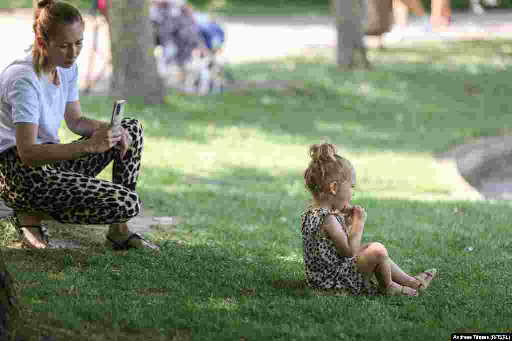 O femeie și fiica sa se răcoresc lângă lacul din Parcul Alexandru Ioan Cuza din București.