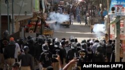 FILE: Pakistani policemen fire teargas shells towards protesters during a protest in Karachi.