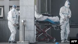 Medical staff members carry a patient at a hospital in China where victims are treated amid a virus outbreak.