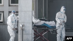 Медицинские работники несут пациента в больницу «Цзиньиньтань» в Ухане, центральной провинции Китая Хубей. 18 января 2020 года.