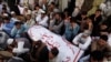 FILE: Shi'ite Muslim men from Pakistan's ethnic Hazara minority mourn around the coffins of their relatives, who were killed in a shooting attack, in Quetta in October 2017.
