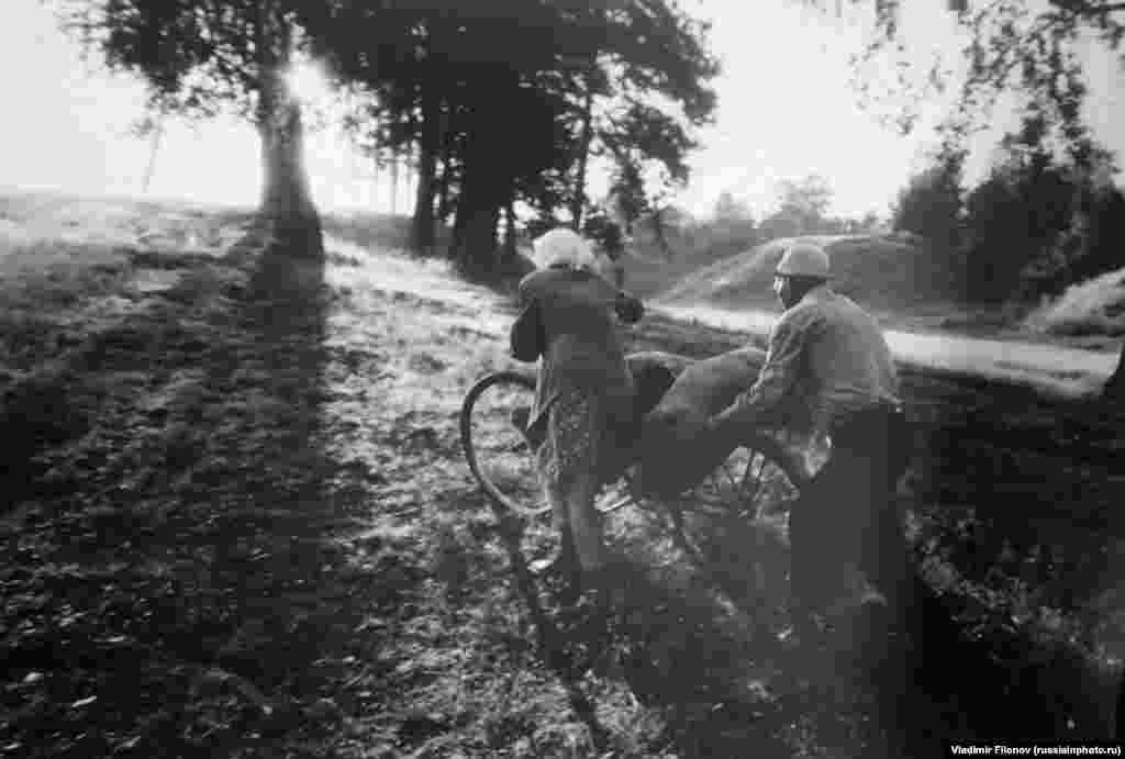 Пара толкает велосипед по весенней грязи, 1980 год.
