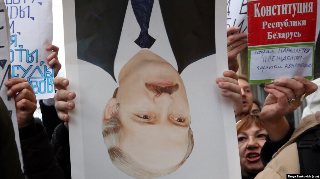 A protester holds a portrait of Belarusian President Alyaksandr Lukashenka upside down during a protest in Minsk.