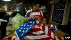 A woman folds U.S. national flags at a shop in Yangon, Burma, ahead of a visit by U.S. President Barack Obama.