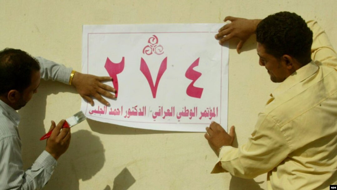 Iraqi men put up election posters on a street in Al-Najaf earlier this month.