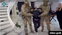 Pjesëtarë të Shërbimit të Sigurisë së Ukrainës arrestojnë një të dyshuar për spiunim, më 9 maj.