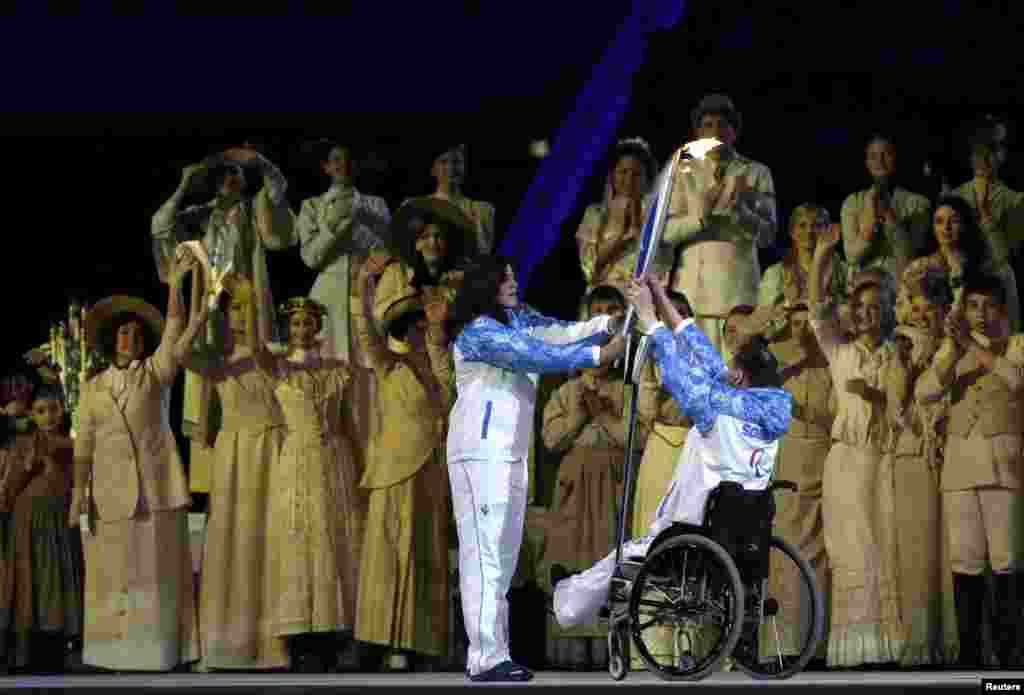 4-кратный паралимпийский чемпион Алексей Ашаратов передает олимпийский факел паралимпийской чемпиоке Ольге Семеновой на церемонии открытия XI зимних Паралимпийских Игр в Сочи