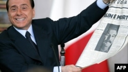 Italy's Prime Minister Silvio Berlusconi shows an old newspaper during his end-of-year news conference in Rome, 23 December 2005. Berlusconi blamed his political foes for an investigation by Italy's antitrust authority for alleged conflict of interest ove