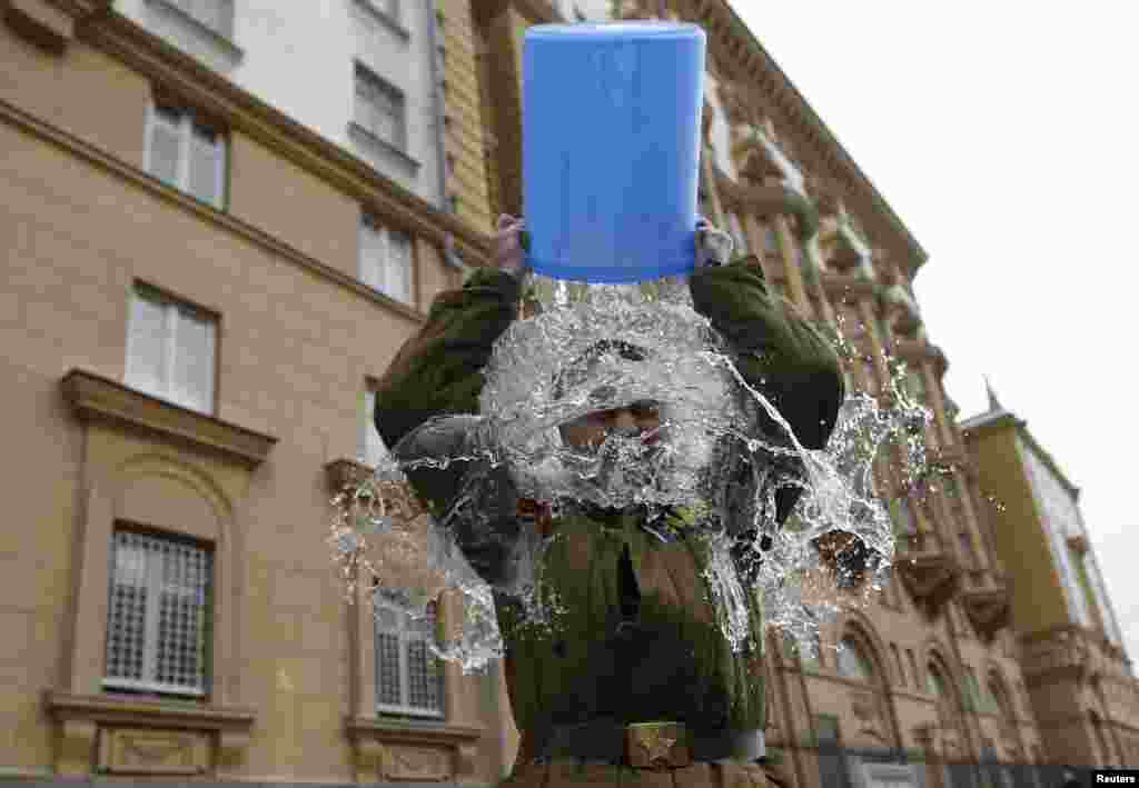 Aleksei Didenko, a deputy in the Russian State Duma, dumps a bucket of cold water on himself in front of the American Embassy in Moscow. Didenko said he was performing the ice-bucket challenge not only to raise awareness for ALS but also to protest against the new U.S. Ambassador to Russia John Tefft and what Didenko called &quot;anti-Russian American propaganda.&quot; (Reuters/Maxim Zmeyev)