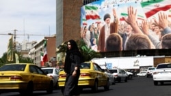 27-nji aprelde Tähranda bir aýal Eýranyň aýatdan öten ýokary ruhany lideri Aýatolla Ali Hameneýiniň suraty goýlan bilbordyň ýanyndan geçip barýar.