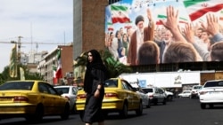 A woman walks past a billboard featuring an image of late Supreme Leader Ayatollah Ali Khamenei in Tehran on April 27.