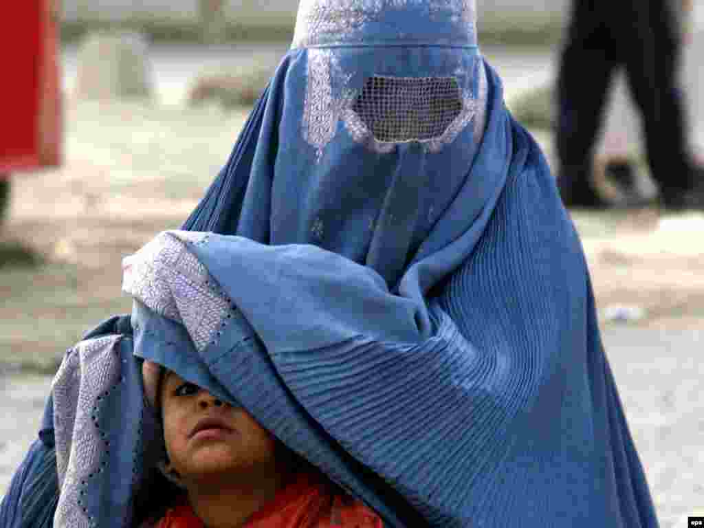 An Afghan woman sits with her son as she begs for money in Kabul. - Photo by S. Sabawoon for epa