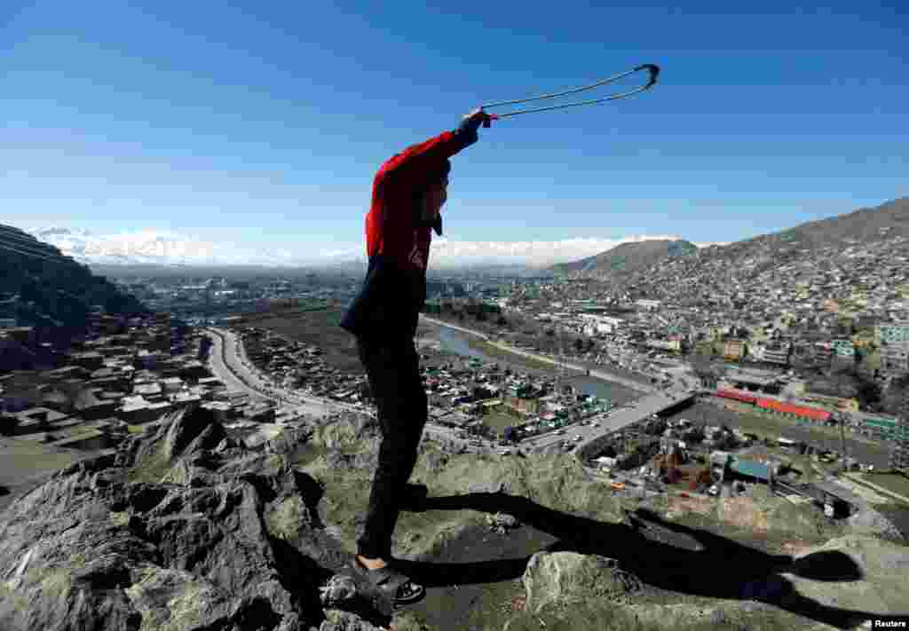 An Afghan boy plays with a sling outside his house on a hilltop in Kabul. (Reuters/Omar Sobhani)