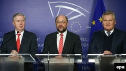 Former European Parliament President Pat Cox (left), former Polish President Aleksander Kwasniewski (center), and European Parliament President Martin Schulz address a press conference at the European Parliament in Brussels on December 4.
