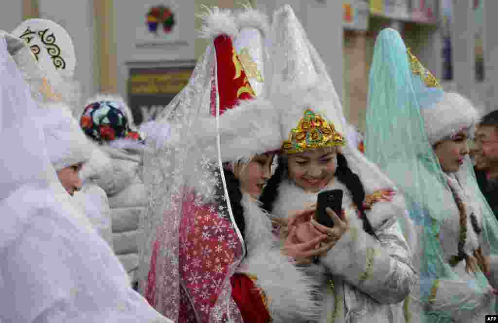 Women dressed as "Snegurochka" (Snow Maiden) look at a mobile phone during the New Year's parade in the Kyrgyz capital, Bishkek, on December 31. (AFP/Vyacheslav Oseledko)