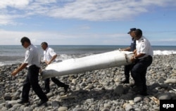 Офицеры несут обломки неизвестного самолета, найденного в водах вблизи французского острова Ла Реюнион. 29 июля 2015 года.