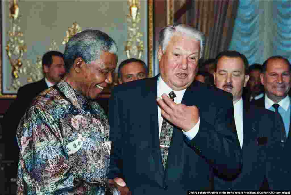 Ельцин с президентом ЮАР Нельсоном Манделой в Нью-Йорке во время торжеств по поводу 5-летия Организации Объединенных Наций в октябре 1995 года. Два пальца левой руки Ельцин потерял в возрасте 11 лет. В своих мемуарах &quot;Исповедь на заданную тему&quot; он рассказывает, как пробрался на склад с оружием:&nbsp;&quot;Ночью пролез через три полосы колючей проволоки и, пока часовой находился на другой стороне, пропилил решётку в окне, забрался внутрь, взял две гранаты РГД-33 с запалами и, к счастью, благополучно (часовой стрелял бы без предупреждения) выбрался обратно. Уехали километров за 60 в лес, решили гранаты разобрать. Ребят все же догадался уговорить отойти метров за сто: бил молотком, стоя на коленях, а гранату положил на камень. А вот запал не вынул, не знал. Взрыв... и пальцев нет&quot;.