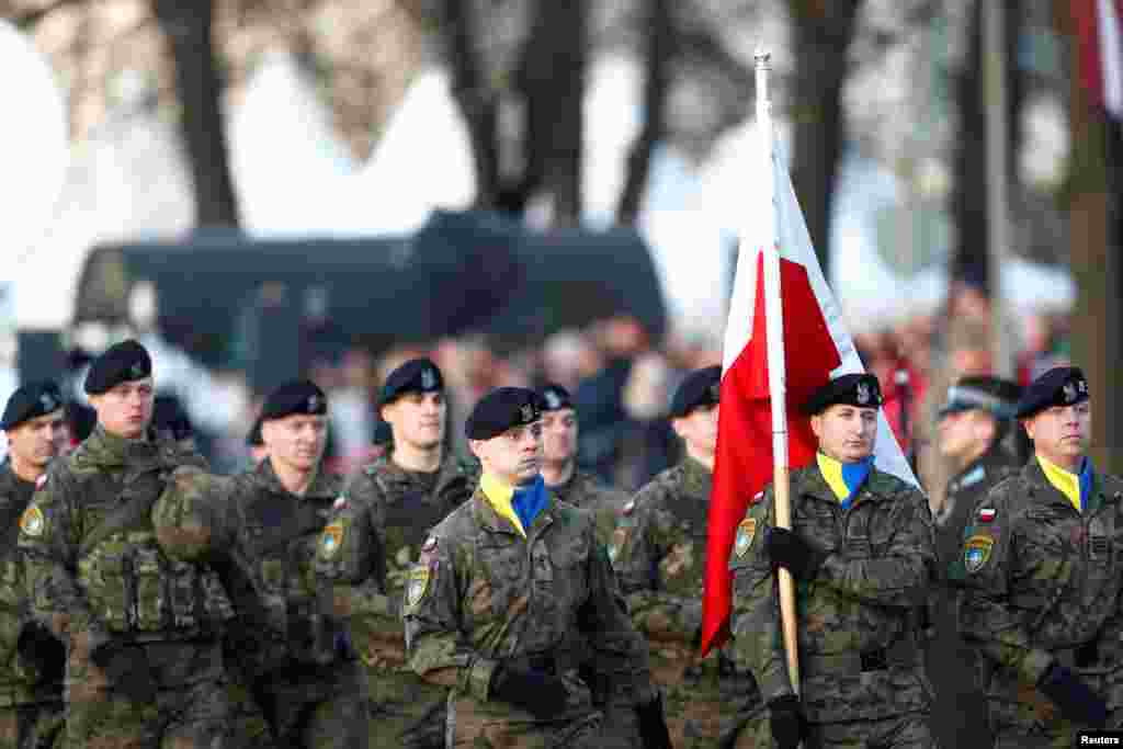 Польські військові у жовто-блактиних хустках несуть прапор Польщі