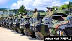 Ushtarët e Forcës së Sigurisë së Kosovës qëndrojnë mbi automjetet e blinduara të dhuruara nga SHBA-ja. 