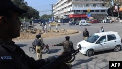 Policemen stand guard at a security checkpoint in Karachi.