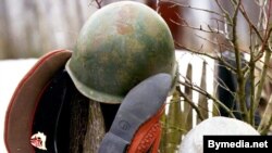 Belarus -- Soldier's peak-cap, soldier's helmet, bedroom-slippers and pig-iron pot on a fence, Apr1999