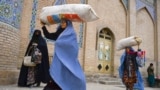 AFGHANISTAN -- Burqa-clad women carry their belongings as they walk past the Jama Mosque in Herat, December 3, 2020