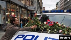 A woman places flowers on a police vehicle after a memorial march to mourn for the victims of the killing spree and bomb blast in Oslo on July 25.