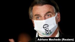 Žair Bolsonaro na konferenciji za medije sa maskom na kojoj je njegov lik, Brazil, 22. maj 2020. 