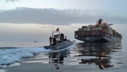 یک قایق توپدار سپاه پاسداران در حال نزدیک شدن به یک کشتی کانتینربر در تنگهٔ هرمز برای توقیف آن