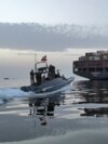 Катер иранского Корпуса стражей исламской революции (КСИР) приближается к грузовому судну в Ормузском проливе