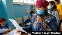 A voter studies the ballot during a parliamentary election in the village of Besh-Kungey on October 4, 2020. 