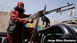 A Taliban fighter rides on a pickup truck mounted with a weapon in Kabul.