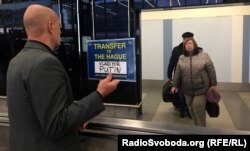 Чоловік із табличкою «Трансфер в Гаагу для Володимира Путіна» у Празькому аеропорту імені Вацлава Гавела. Прага, 26 листопада 2017 року